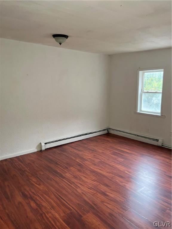 spare room featuring hardwood / wood-style flooring and baseboard heating