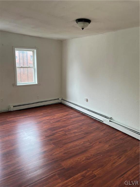 empty room with a baseboard radiator and dark wood-type flooring