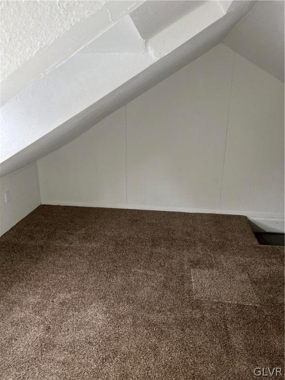 bonus room with vaulted ceiling and carpet flooring