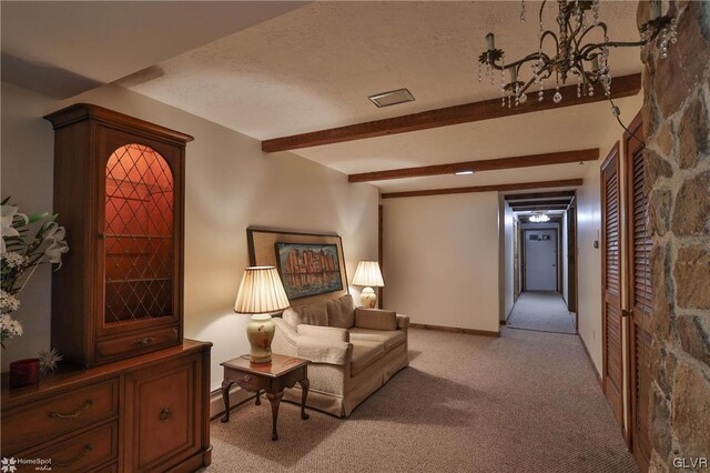 sitting room with a textured ceiling, beam ceiling, a notable chandelier, and light carpet