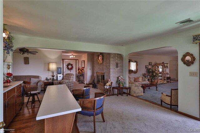 living room with brick wall, ceiling fan, dark hardwood / wood-style flooring, and a brick fireplace