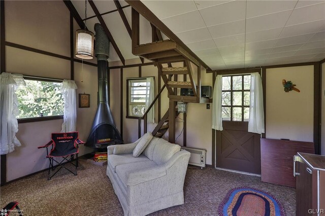 carpeted entryway with a wood stove and lofted ceiling