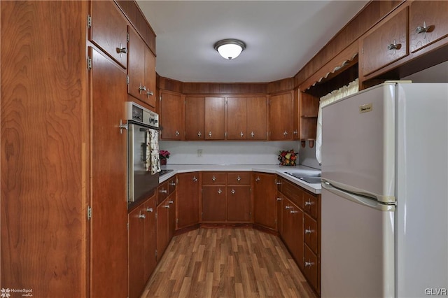 kitchen featuring light wood-type flooring, stainless steel oven, sink, and white fridge