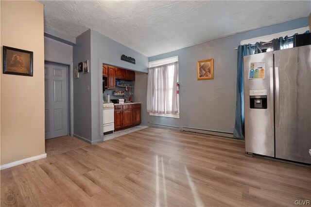 interior space featuring a textured ceiling, light hardwood / wood-style flooring, baseboard heating, stainless steel fridge with ice dispenser, and vaulted ceiling