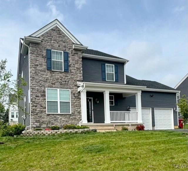 view of front of property featuring a porch, a front yard, and a garage