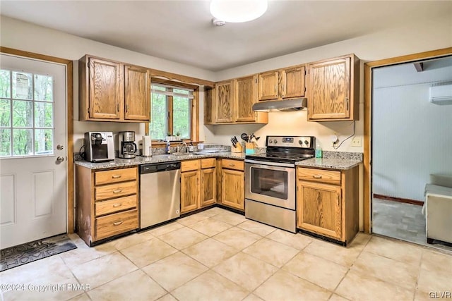 kitchen with a wealth of natural light, light stone counters, appliances with stainless steel finishes, and a wall mounted air conditioner