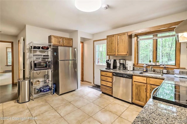 kitchen featuring a baseboard heating unit, sink, appliances with stainless steel finishes, light tile patterned floors, and light stone countertops