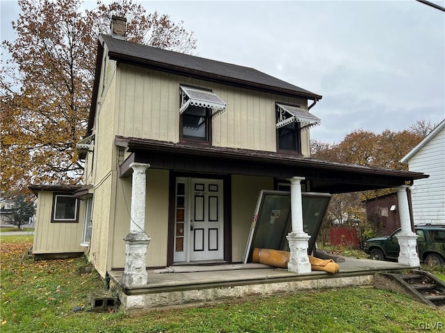 back of house featuring covered porch and a yard