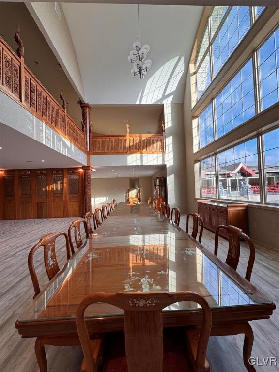 dining area featuring high vaulted ceiling, hardwood / wood-style flooring, a chandelier, and plenty of natural light