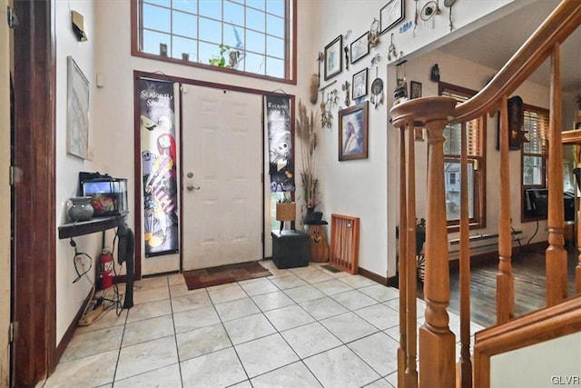 entryway with baseboard heating, a towering ceiling, and light tile patterned floors