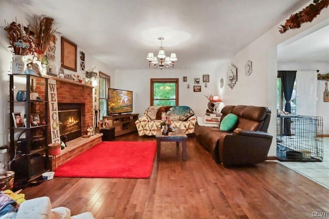 living room featuring a brick fireplace, a chandelier, and wood-type flooring