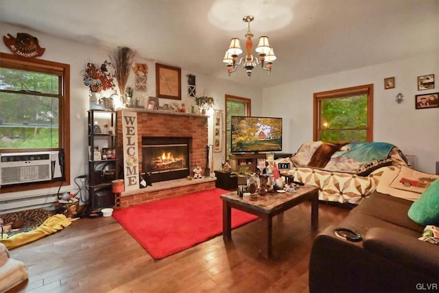 living room featuring a notable chandelier, a healthy amount of sunlight, hardwood / wood-style flooring, and a fireplace