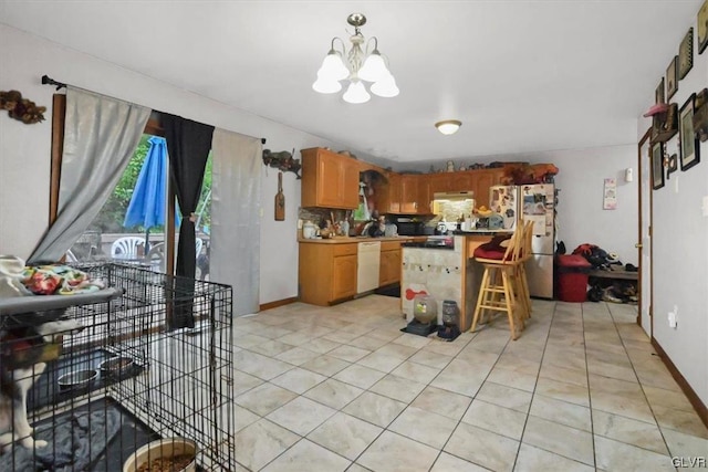 kitchen with a kitchen breakfast bar, stainless steel fridge, white dishwasher, decorative light fixtures, and a chandelier