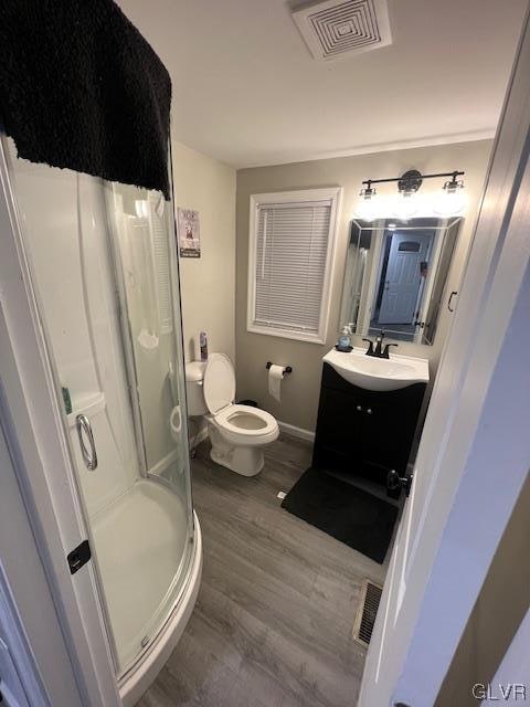 bathroom with toilet, vanity, hardwood / wood-style flooring, and walk in shower