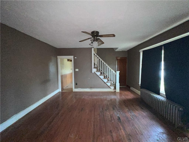 empty room featuring a textured ceiling, radiator heating unit, ceiling fan, and dark wood-type flooring