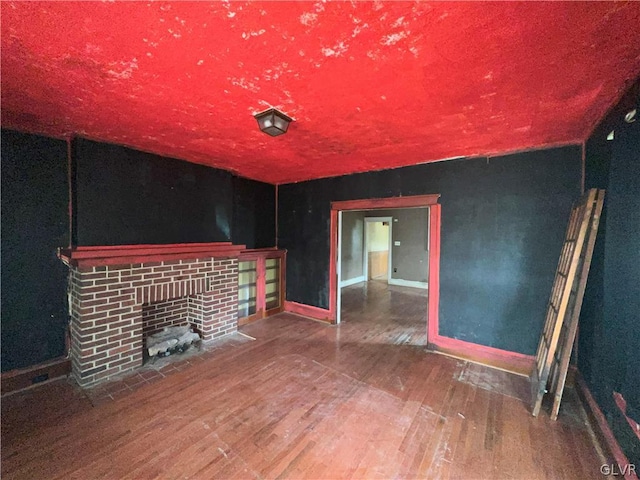 unfurnished living room featuring a brick fireplace and hardwood / wood-style floors