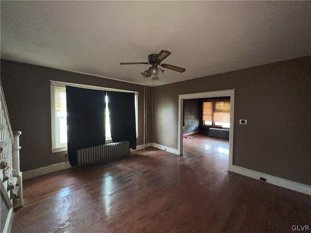 unfurnished living room featuring a textured ceiling, ceiling fan, radiator heating unit, and dark hardwood / wood-style flooring