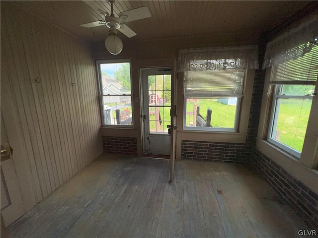 unfurnished sunroom featuring ceiling fan and a wealth of natural light