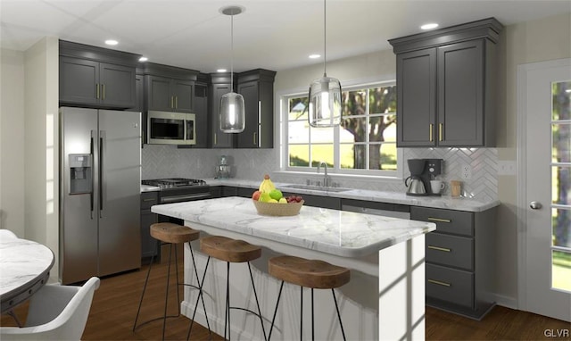 kitchen with appliances with stainless steel finishes, dark hardwood / wood-style flooring, sink, decorative light fixtures, and a kitchen island