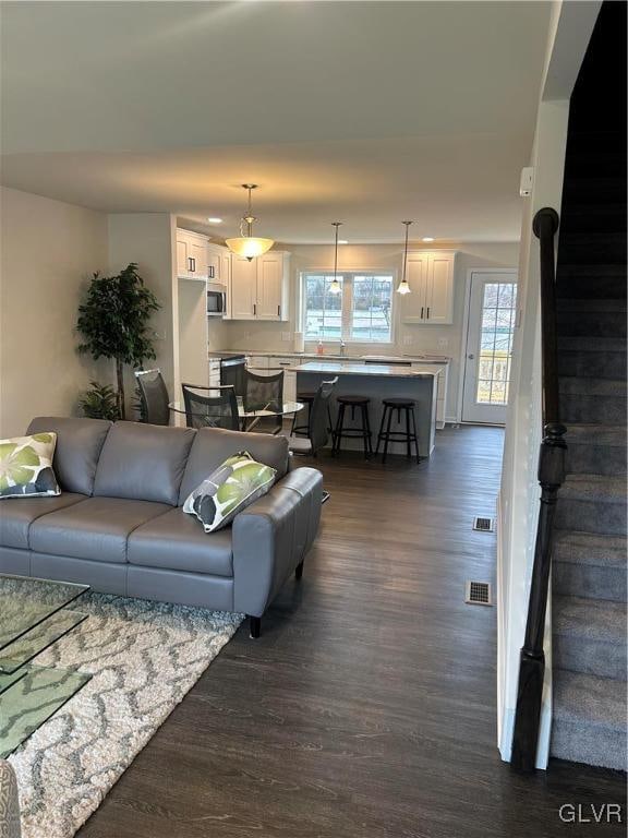 living room with plenty of natural light and dark wood-type flooring