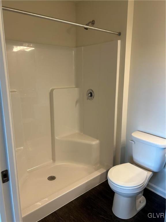 bathroom with a shower, hardwood / wood-style floors, and toilet