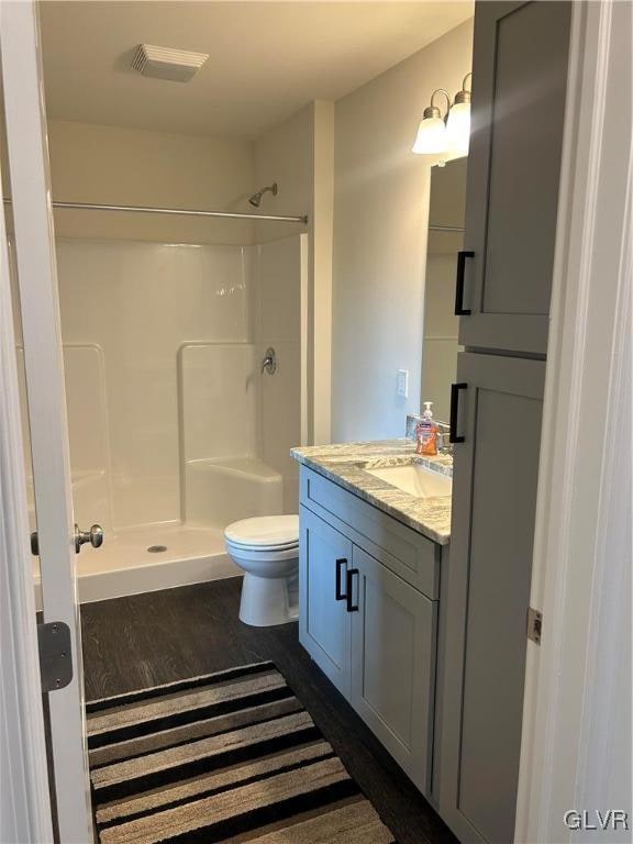 bathroom featuring a shower, hardwood / wood-style floors, and toilet