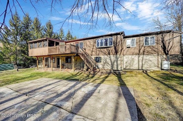 back of property featuring a wooden deck and a lawn