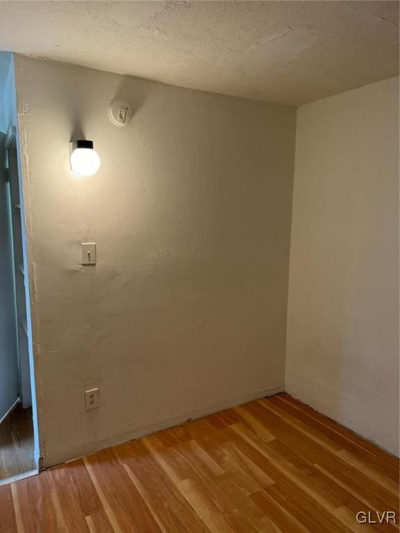 spare room featuring wood-type flooring and a textured ceiling