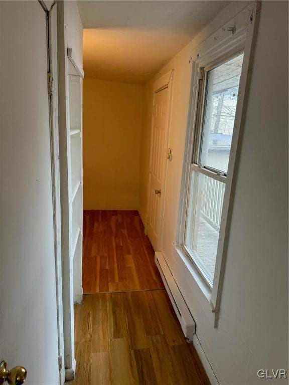 corridor with a baseboard heating unit and hardwood / wood-style flooring