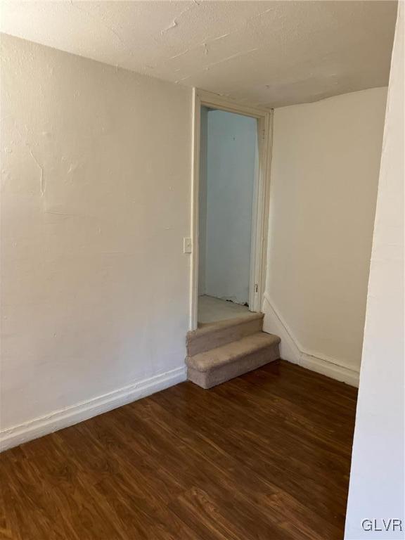 empty room with a textured ceiling and dark hardwood / wood-style floors