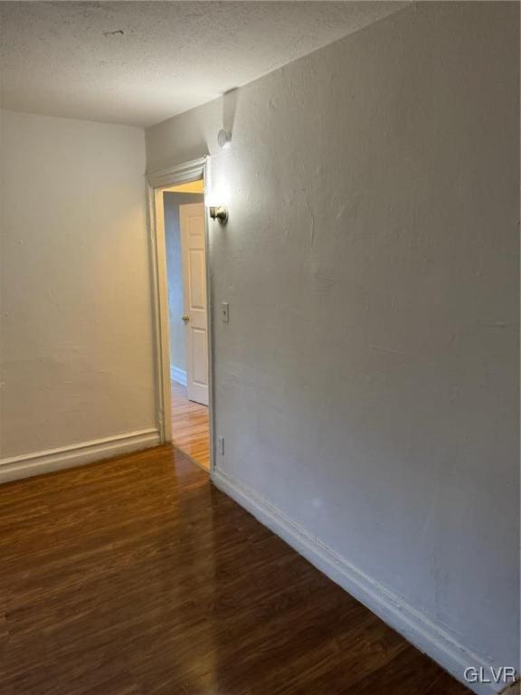 spare room with a textured ceiling and dark hardwood / wood-style flooring