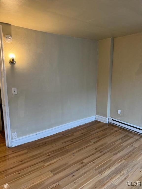 spare room with light wood-type flooring and a baseboard heating unit