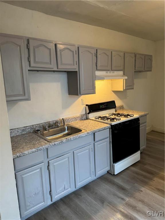 kitchen with gray cabinets, sink, dark hardwood / wood-style flooring, and white gas range oven