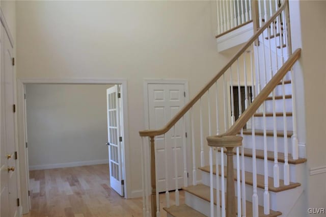 stairway featuring wood-type flooring and a towering ceiling