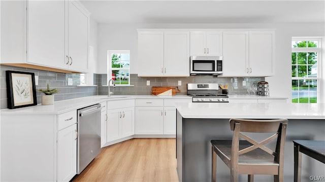 kitchen featuring decorative backsplash, sink, a kitchen bar, light hardwood / wood-style floors, and appliances with stainless steel finishes