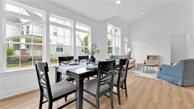 dining area featuring light hardwood / wood-style floors, high vaulted ceiling, and plenty of natural light