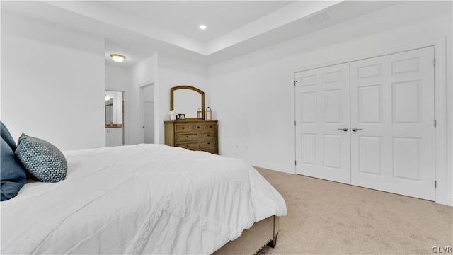 carpeted bedroom featuring a closet and a raised ceiling