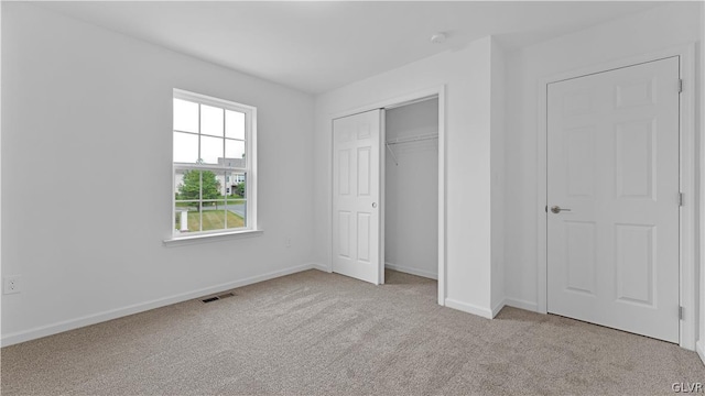 unfurnished bedroom featuring light carpet and a closet