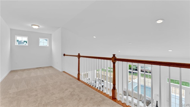 corridor with plenty of natural light, light carpet, and vaulted ceiling