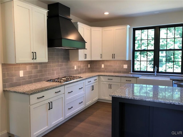 kitchen with stainless steel appliances, extractor fan, white cabinets, and light stone counters