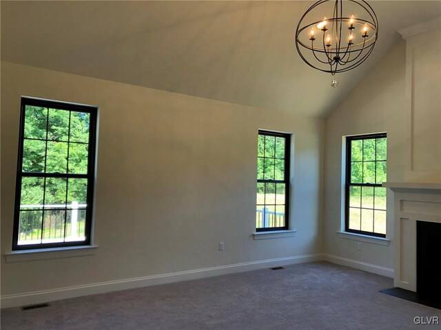 unfurnished living room with dark colored carpet, vaulted ceiling, and an inviting chandelier