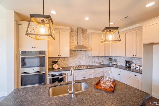 kitchen with wall chimney range hood, hanging light fixtures, stainless steel appliances, and sink