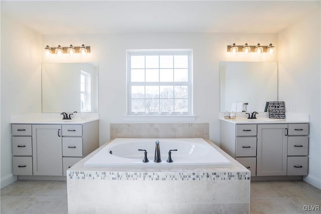 bathroom featuring vanity, tile patterned flooring, and tiled bath