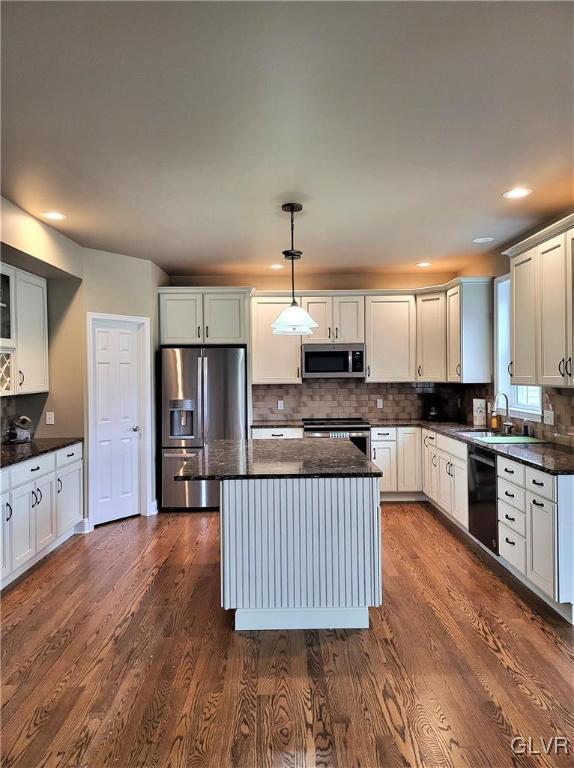 kitchen featuring hanging light fixtures, tasteful backsplash, appliances with stainless steel finishes, a center island, and dark hardwood / wood-style flooring