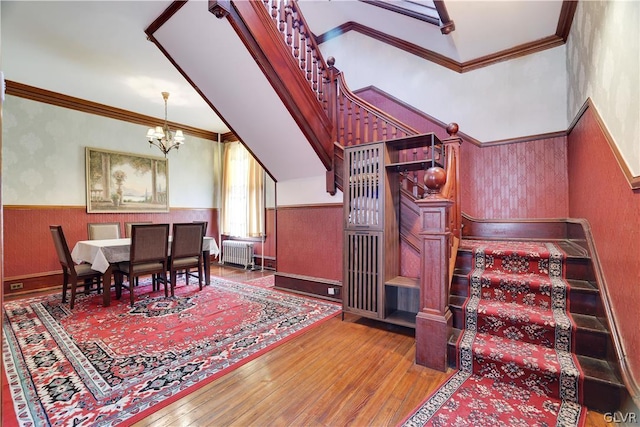 dining space featuring radiator, a wainscoted wall, crown molding, and stairs