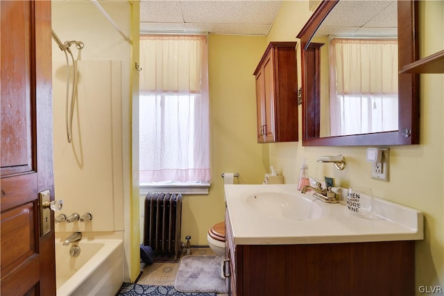 full bath featuring a drop ceiling, radiator, toilet, vanity, and washtub / shower combination