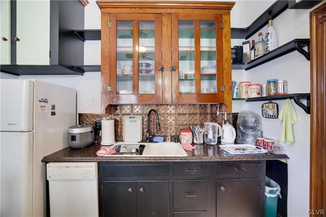 kitchen featuring dark stone countertops, white appliances, tasteful backsplash, and sink