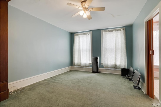 carpeted empty room featuring radiator, baseboards, and a ceiling fan