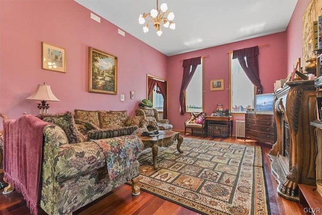 living room featuring wood-type flooring, radiator, and a notable chandelier