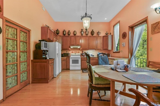 kitchen featuring a chandelier, pendant lighting, white appliances, and light wood-type flooring